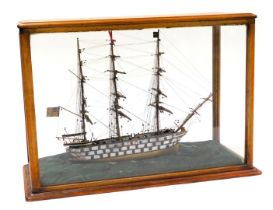 A wooden model of a late 18thC warship, three masted and fully rigged, on a sea base, mahogany cased