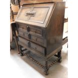 A Jacobean style oak bureau, with fall flap over three graduated drawers and barley twist framing.