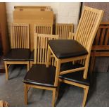 A modern oak finish dining table, together with six chairs with brown leatherette overstuffed seats.