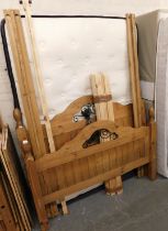 A pine double bed frame, comprising head and foot boards, side rails and a mattress.