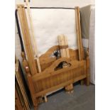 A pine double bed frame, comprising head and foot boards, side rails and a mattress.