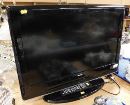 A Bush 26" flat screen TV, with remote control, model number R7198RA005853.