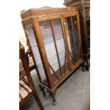 An early 20thC oak display cabinet, the raised shaped back above two glazed doors enclosing glass sh