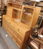 A teak sideboard, with single glazed door, series of shelves, fall front, three drawers below on bas