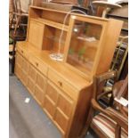 A teak sideboard, with single glazed door, series of shelves, fall front, three drawers below on bas