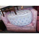 A mid century two seater sofa, upholstered in pink foliate fabric, together with an oval footstool w