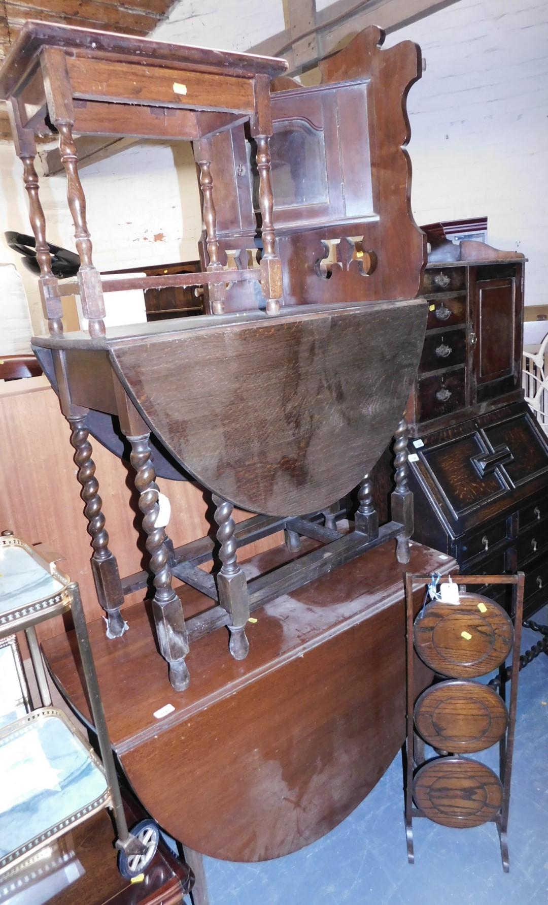 A drop leaf table raised on barley twist supports with gate leg action, a three tier cake stand, a d