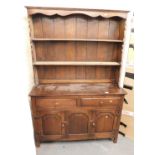 An oak stained dresser, with plate rack over base unit of two drawers over three panelled doors, rai