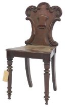 A Victorian mahogany hall chair, the solid carved back with shield crest and scroll motifs, with a s