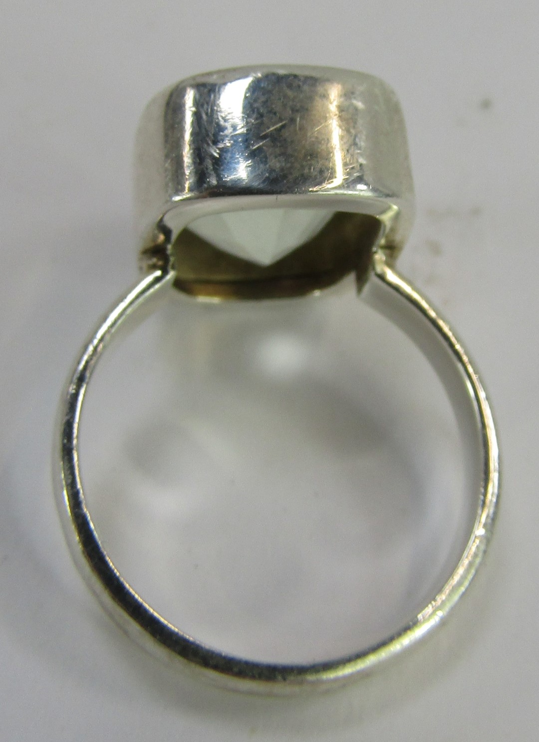 A dress ring, with a rectangular cut and faceted pale green stone, in a rub over white metal border - Image 2 of 3