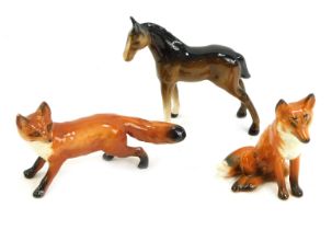 Three Beswick pottery figures, comprising seated fox, standing fox, and brown foal, the foal 9cm hig