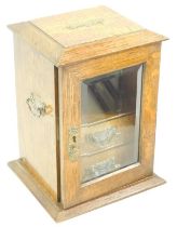 A Victorian oak smoker's cabinet, with twin carrying handles, the bevel glass inset door enclosing a