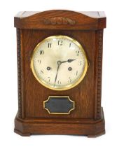 An early 20thC oak cased mantel clock, circular silvered dial bearing Arabic numerals, Junghans A42