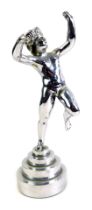 An early 20thC chrome figure, modelled as a Putti with arms and one leg raised, on stepped base, pos