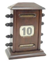 An early 20thC oak perpetual desk calendar, with ebonised turners, displaying day, date and month, o