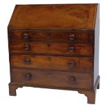 A George III mahogany bureau, the top with a fall, enclosing an arrangement of drawers, recesses and