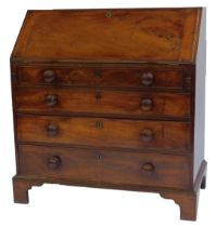 A George III mahogany bureau, the top with a fall, enclosing an arrangement of drawers, recesses and