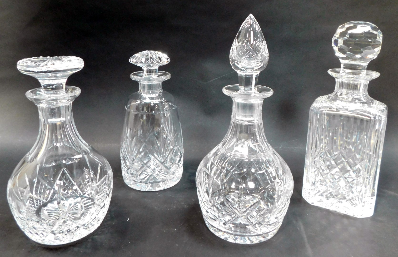Four cut glass decanters, comprising a square decanter and stopper, 28cm high, cylindrical decanter