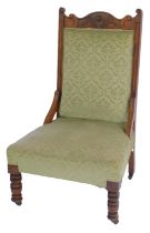 A late 19th/early 20thC walnut framed nursing chair, the floral carved back above an overstuffed gre