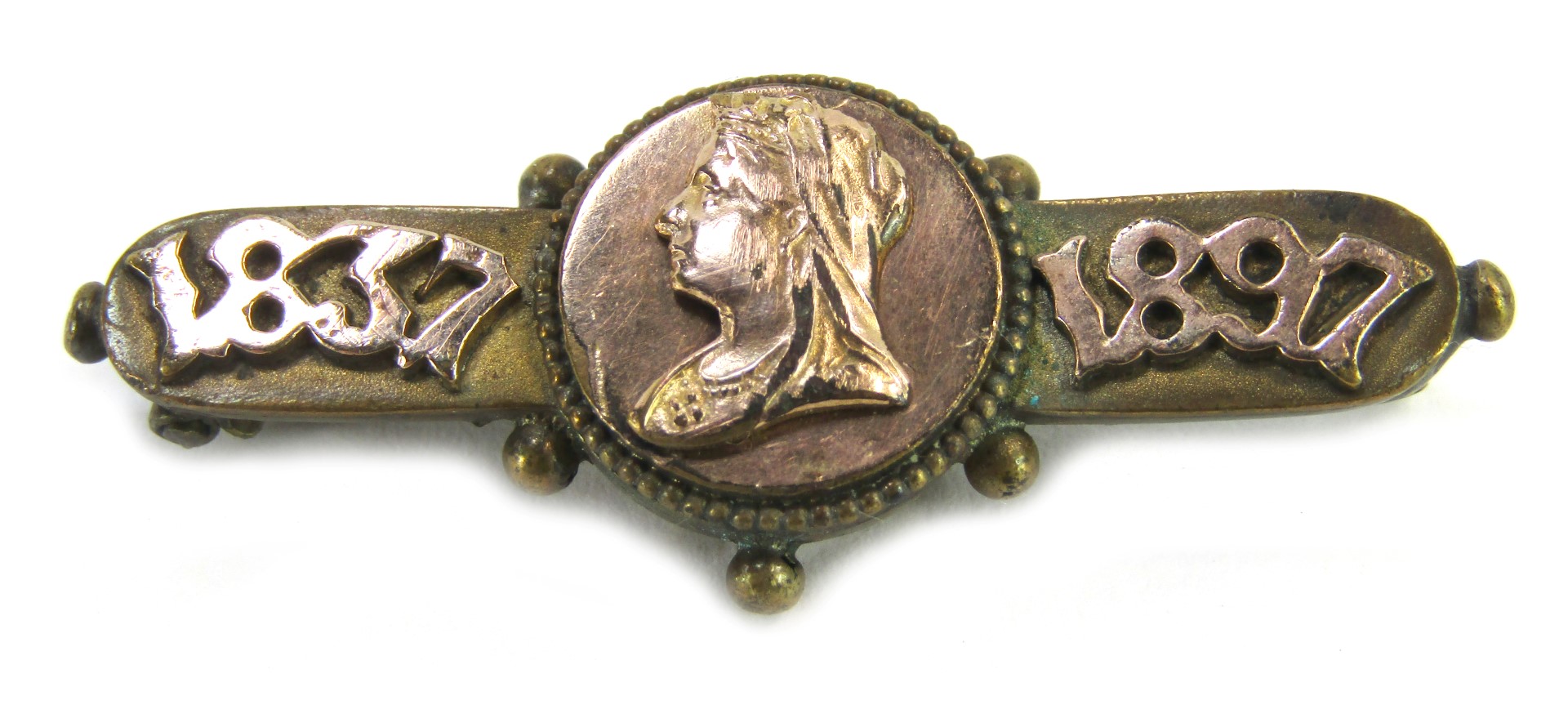 A commemorative bar brooch, dated 1897, with central figure of Queen Victoria, on a brass base frame