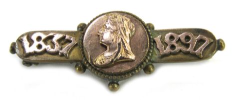 A commemorative bar brooch, dated 1897, with central figure of Queen Victoria, on a brass base frame