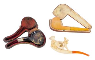 Three pipes, comprising a 19thC meerschaum and amber pipe depicting gentlemen hunting, 13cm wide, a