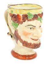 An early 19thC Staffordshire pearl ware mug, moulded as Bacchus, 11.5cm high.