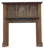 An early 20thC oak fire surround, the carved and moulded top above three arched sections, with carve