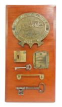 A wooden plaque bearing various door furniture, comprising a J Grove & Son brass plaque, Grove & Son