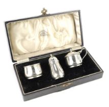 A George VI silver three piece cruet set, comprising salt with blue glass liner, pepper shaker and m