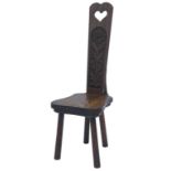 A 20thC Welsh oak spinning chair, the narrow tapering back with pierced heart motif above a flower c