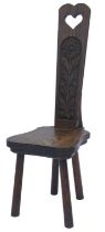 A 20thC Welsh oak spinning chair, the narrow tapering back with pierced heart motif above a flower c