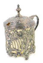 A 19thC white metal Continental mustard pot, with rococo scroll and pierced decoration and shield be