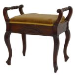 A late 19thC mahogany piano stool, the turned cylindrical handles above a carved front and side pane