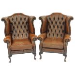 A pair of brown leather wing back armchairs, with button back, stud work and moveable seat, on mahog