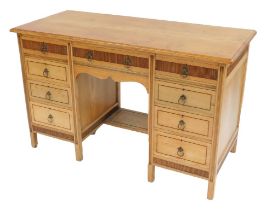 An early 20thC blonde ash pedestal desk by Shoolbred and Co, the top with a moulded edge above centr