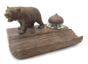 A 20thC Black Forest desk stand, surmounted by a carved bear, beside glass ink well with carved stop