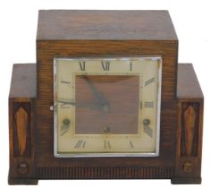 A 1950/60s oak cased mantel clock, the sectional top with a square silvered Roman numeric dial and b