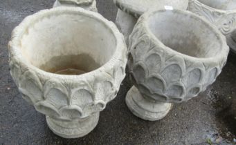 A pair of reconstituted stone pineapple planters, with shaped sides on a circular foot, 50cm high, 3