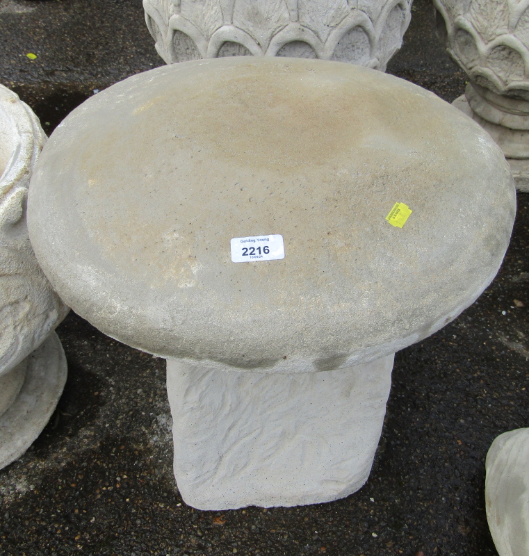 A reconstituted stone saddle stone, the circular top on a moulded base, 42cm high, 47cm wide.
