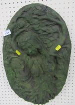 A green painted composition wall plaque, depicting a scantily clad female amongst foliage, 53cm high