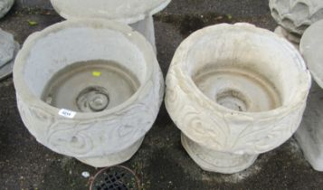 A pair of reconstituted stone garden urns, each of scroll and feather design, on a circular foot, 42
