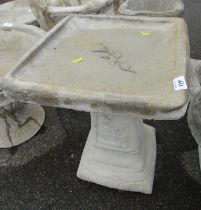 A reconstituted stone bird table, the square top with raised emblem, on column base, 50cm high, 39cm