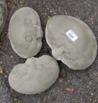 Three reconstituted stone pebble head figures, the largest 20cm wide, the smallest 18cm wide.