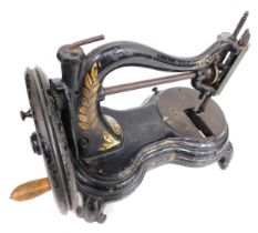 A 19thC sewing machine, on black cast base, with gilt leaf decoration and spun handle, on splayed le