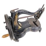 A 19thC sewing machine, on black cast base, with gilt leaf decoration and spun handle, on splayed le