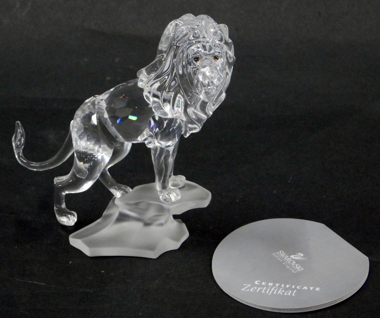 A Swarovski crystal figure group of a roaring lion, on rocked perch, 13cm high, boxed with certifica