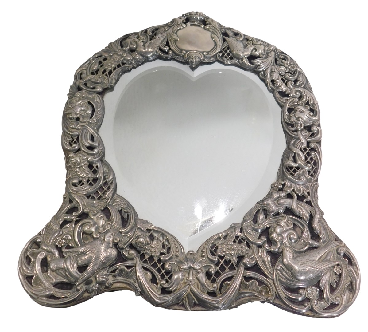 A late Victorian silver dressing table mirror, the bevelled love heart shaped mirror panel surrounde