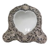 A late Victorian silver dressing table mirror, the bevelled love heart shaped mirror panel surrounde