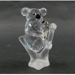 A Swarovski crystal figure group of two koala bears, mother and baby, perched on branch, with black